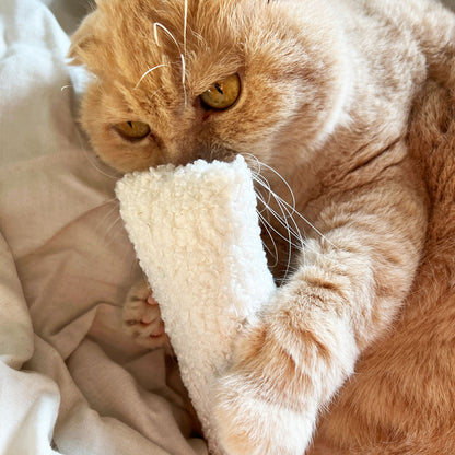 Chat jouant avec un jouet Maxi Berlingot en tissu bouclette blanc. Un jouet apaisant et multifonction pour les moments de repos ou de jeu.